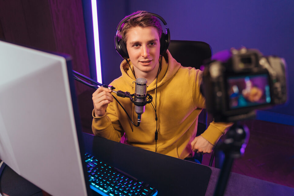 A photo of a streamer sat at a desk with a mic arm and streaming set up